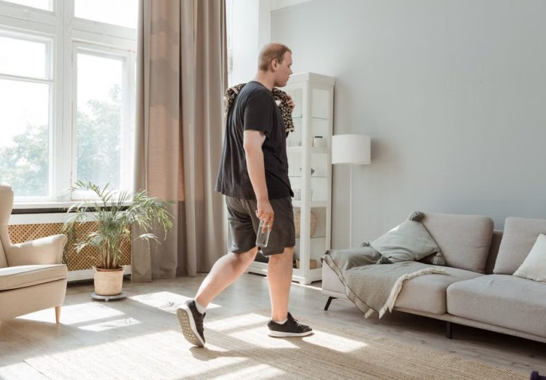 Plus size man in active wear working out in a sunny, modern living room.