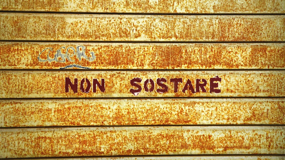 Rusty metal door with "non sostare" text.